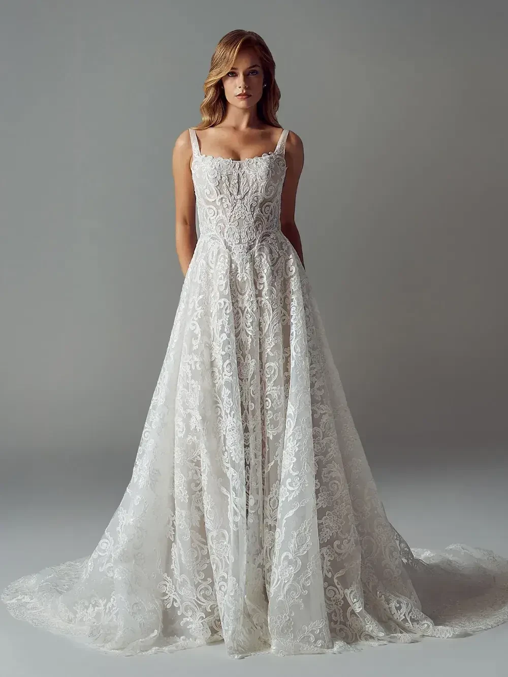 A model wearing an elegant white lace wedding gown with a fitted bodice and a flowing skirt.