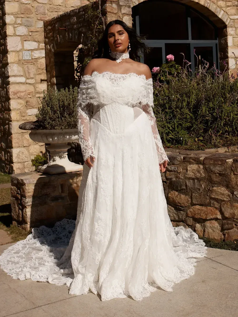 model is wearing an off the shoulder lace a-line bridal gown