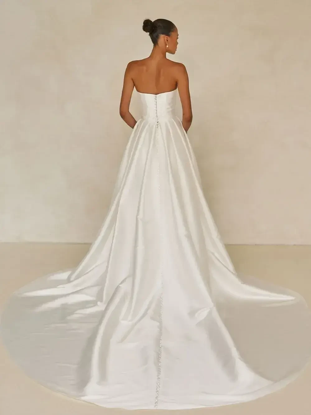 A woman wearing a strapless white gown, standing with her back to the camera.